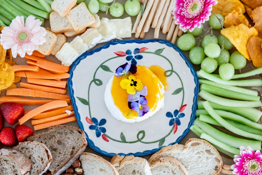 Close-up of a hand-painted Portuguese plate with fresh cheese, honey and edible pansies