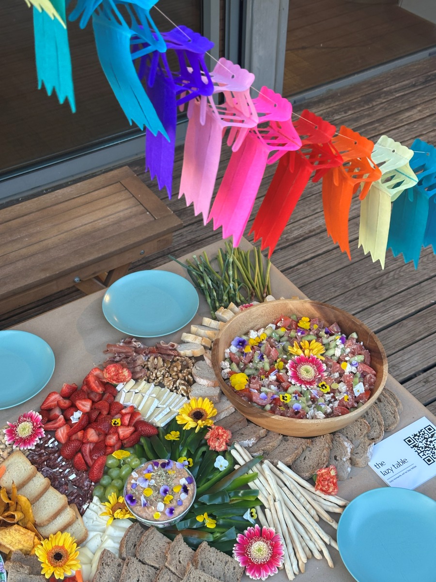 A colourful grazing table with festive bunting on a sunny terrace