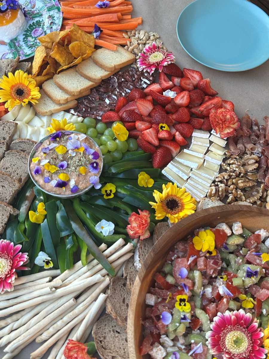 Overhead view of an abundant grazing table with dips, strawberries and flowers