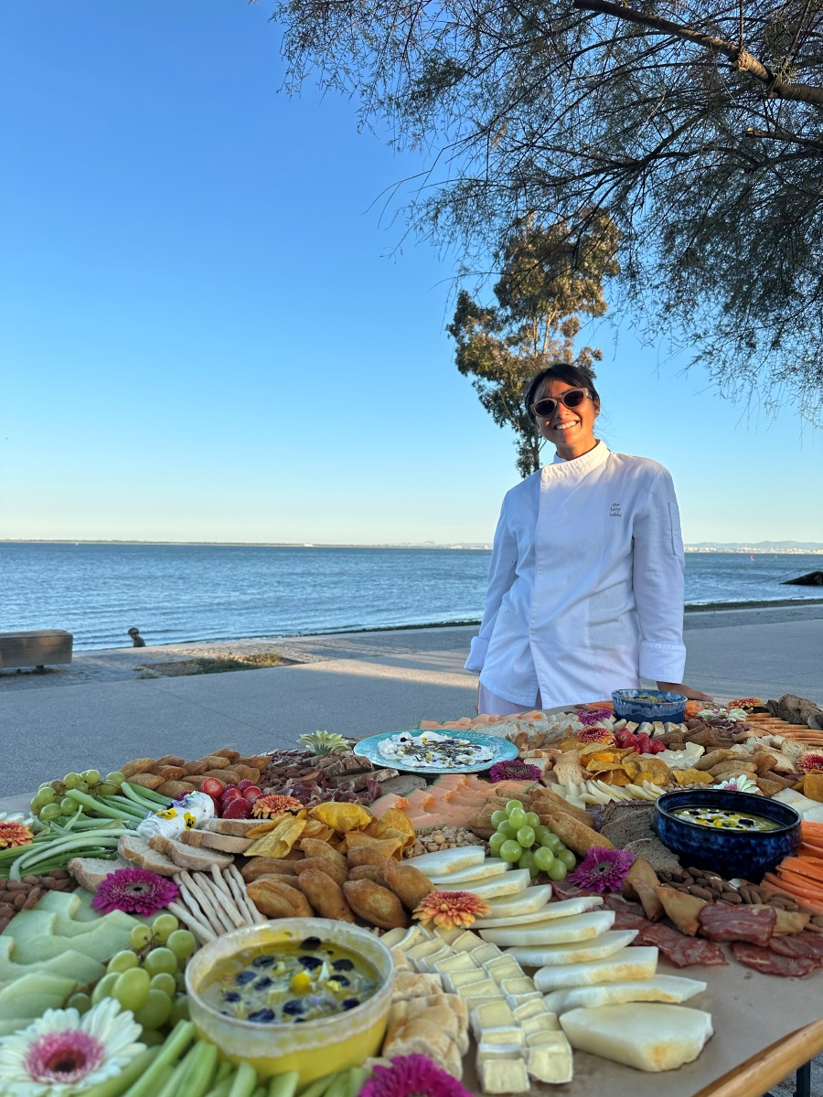 The Lazy Table stylist beside a waterfront grazing table