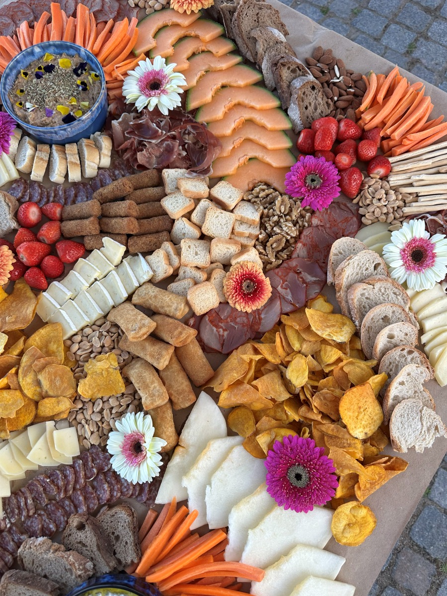 Overhead grazing table layered with melon, cured meats, cheeses and flowers