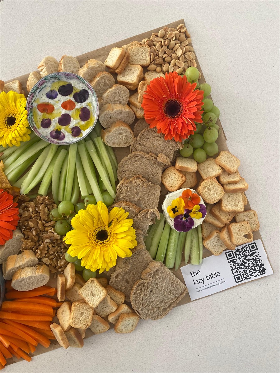 Grazing board with bright gerbera flowers and The Lazy Table card