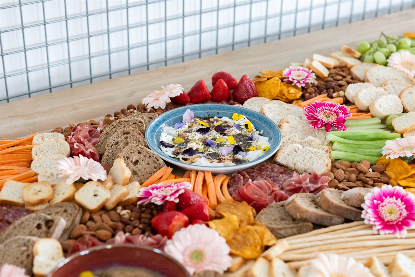 A beautifully styled grazing table with charcuterie, cheese, fresh fruit and edible flowers