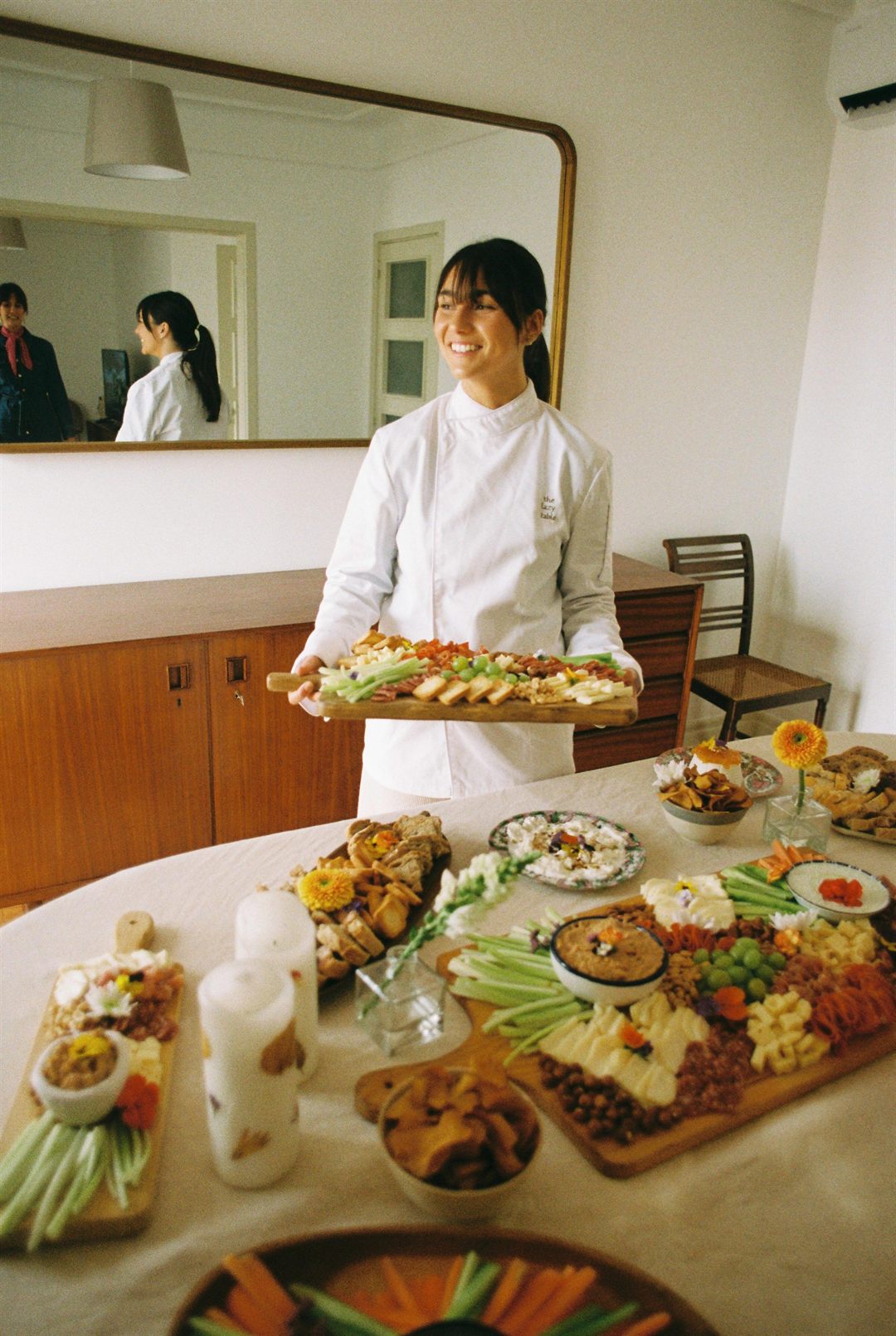 Inês of The Lazy Table smiling and holding a hand-styled grazing board